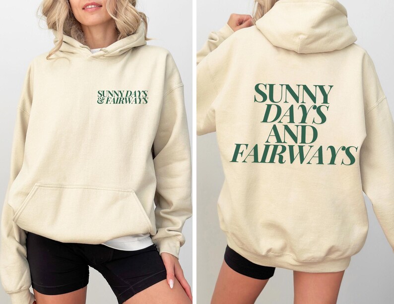 beige golf themed hoodie with sunny days and fairways in a bold, trendy font on the back of the shirt. On the front, is a small sunny days and fairways graphic on the left chest