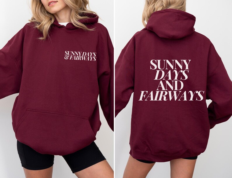maroon golf themed hoodie with sunny days and fairways in a bold, trendy font on the back of the shirt. On the front, is a small sunny days and fairways graphic on the left chest