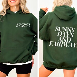 forest green golf themed hoodie with sunny days and fairways in a bold, trendy font on the back of the shirt. On the front, is a small sunny days and fairways graphic on the left chest