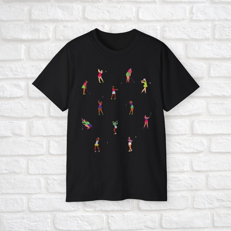 Może przedstawiać: Czarny T-shirt z wzorem kobiet grających w golfa w r&oacute;żnych pozach. Kobiety są ubrane w kolorowe ubrania i trzymają kije golfowe.