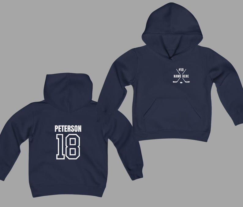 May include: Navy blue hoodie with white text and graphics. The front features a hockey stick and puck design with the text "#18 NAME HERE". The back displays the name "Peterson" above the number "18".