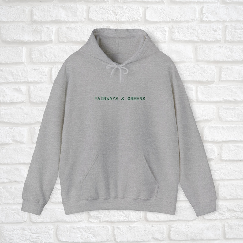 Puede incluir: Una sudadera con capucha gris con un logotipo bordado en verde que dice "Fairways & Greens".