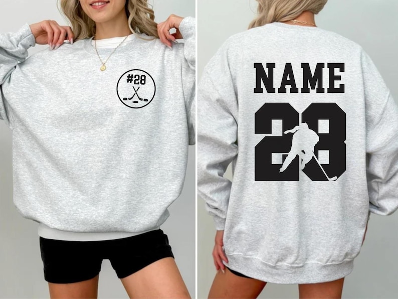 Custom hockey sweatshirt featuring a personalized hockey player name and number design on the back as well as jersey number on the front design.  Also, choose from a variety of hockey player silhouettes to further customize this hockey sweater