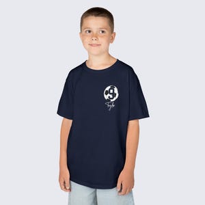 May include: A navy blue t-shirt with a white soccer ball graphic and the number 9 on it. The shirt also has the name "Taylor" written in white below the soccer ball.