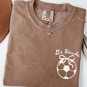 custom soccer t-shirt featuring a unique doodle graphic on the front and back. Customize the team name on the front and player number on the back to show your team pride. Crafted with the comfort colors 1717 tee