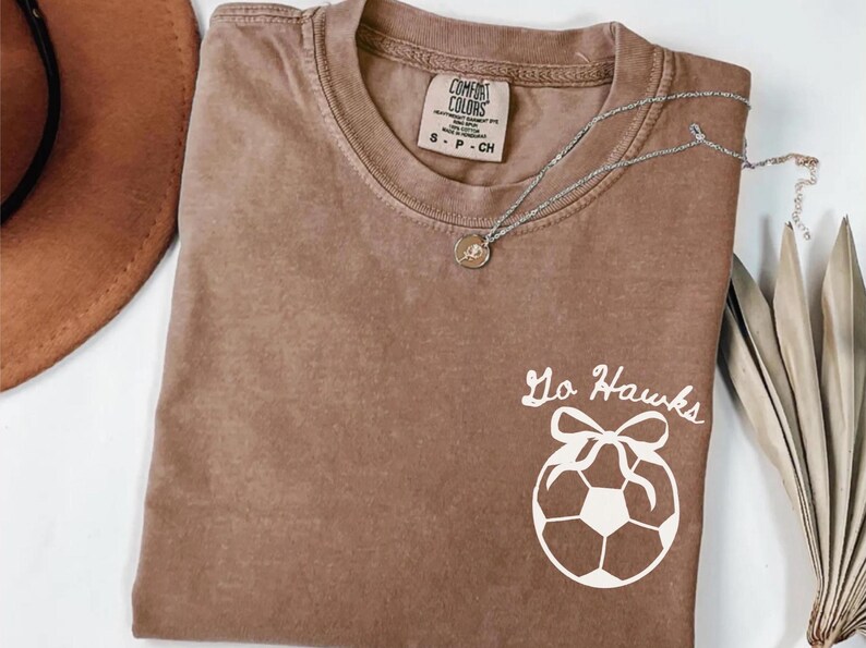 custom soccer t-shirt featuring a unique doodle graphic on the front and back. Customize the team name on the front and player number on the back to show your team pride. Crafted with the comfort colors 1717 tee