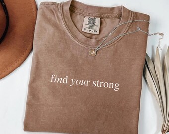 May include: A brown t-shirt with the text "find your strong" printed in white on the front.