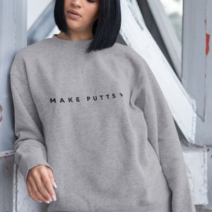 May include: A gray sweatshirt with the text "MAKE PUTTS" printed on the front.