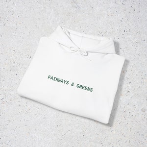 Puede incluir: Sudadera con capucha blanca con el texto "FAIRWAYS & GREENS" en letras verdes.
