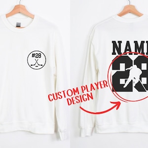Custom hockey sweatshirt featuring a personalized hockey player name and number design on the back as well as jersey number on the front design.  Also, choose from a variety of hockey player silhouettes to further customize this hockey sweater