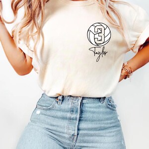 Ivory Comfort Colors 1717 t-shirt with a customizable name and number volleyball graphic.
