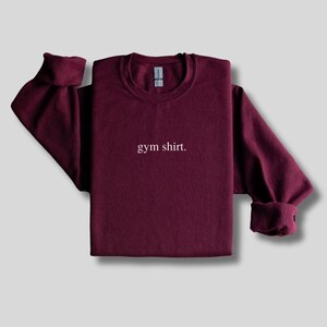 simple maroon gym sweatshirt featuring a minimalist text design. Made with the Gildan 18000 sweatshirt