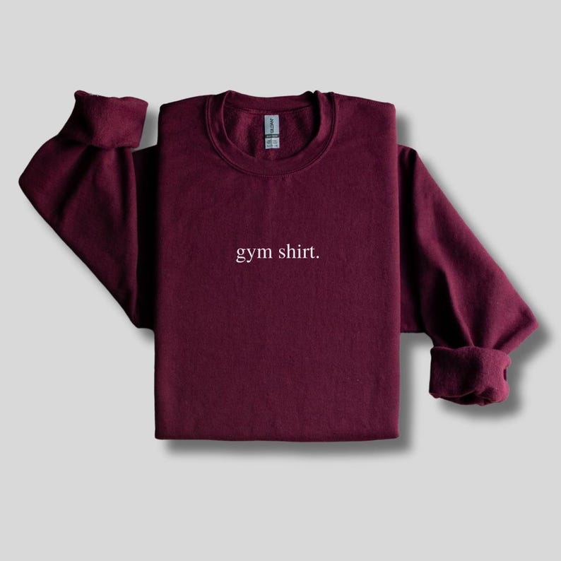 simple maroon gym sweatshirt featuring a minimalist text design. Made with the Gildan 18000 sweatshirt