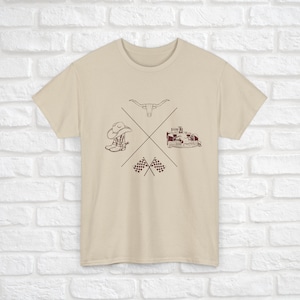 K&ouml;nnte beinhalten: Ein beiges T-Shirt mit einem braunen Grafikdesign, das einen Cowboyhut, Stiefel, einen Stierkopf und karierte Flaggen zeigt.
