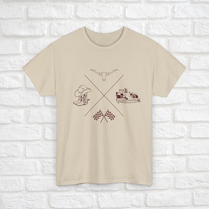 K&ouml;nnte beinhalten: Ein beiges T-Shirt mit einem braunen Grafikdesign, das einen Cowboyhut, Stiefel, einen Stierkopf und karierte Flaggen zeigt.