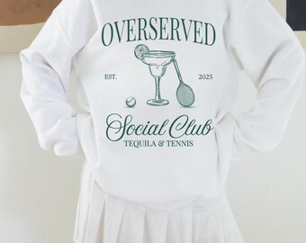 May include: White sweatshirt with a green graphic design that says "Overserved Social Club Tequila & Tennis" with a margarita glass and tennis racket. The text also says "Est. 2025".