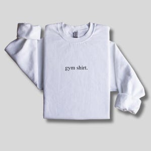 simple white gym sweatshirt featuring a minimalist text design. Made with the Gildan 18000 sweatshirt