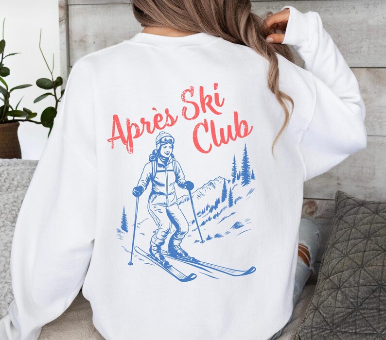May include: White sweatshirt with a blue and red graphic of a skier on a mountain with the text "Apres Ski Club".