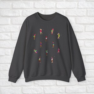 May include: Dark grey sweatshirt featuring a design of women playing golf in different poses. The women are wearing pink, green and white clothing.