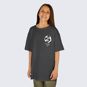 May include: A dark grey t-shirt with a white soccer ball graphic and the number 9. The name "Tyler" is written in white below the ball.