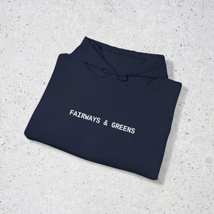 Puede incluir: Una sudadera con capucha azul marino con el texto "FAIRWAYS & GREENS" bordado en blanco en la parte delantera.