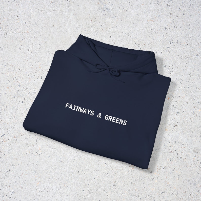 Puede incluir: Una sudadera con capucha azul marino con el texto "FAIRWAYS & GREENS" bordado en blanco en la parte delantera.