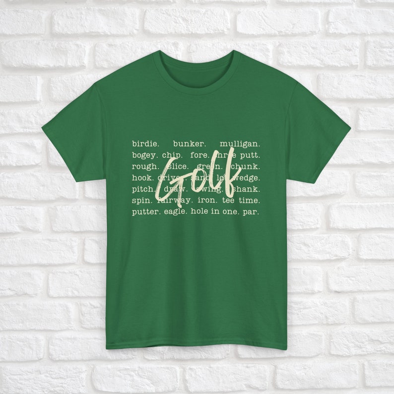 K&ouml;nnte beinhalten: Ein gr&uuml;nes T-Shirt mit dem Wort "Golf" in wei&szlig;er Schrift. Das Wort "Golf" ist umgeben von einer Liste von Golfbegriffen, darunter Birdie, Bunker, Mulligan, Bogey, Chip, Fore, Putt, Rough, Slice, Green, Chunk, Hook, Drive und Low Wedge.