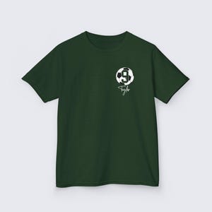 May include: A dark green t-shirt with a white soccer ball graphic and the number 9. The text "Taylor" is written in white below the ball.