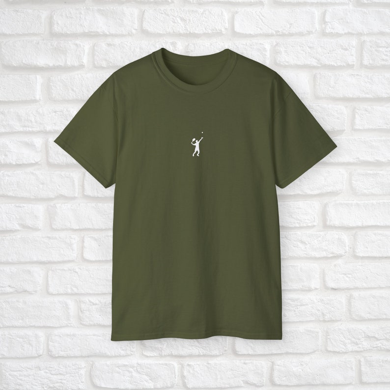 Pu&ograve; includere: Una maglietta verde scuro con una silhouette bianca di una persona che gioca a tennis.