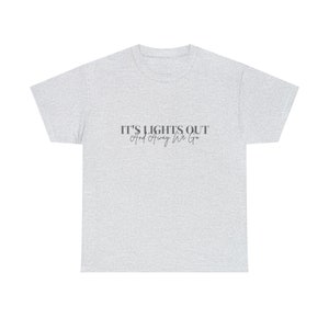 Puede incluir: Una camiseta gris jaspeada con el texto "It's Lights Out And Away We Go!" impreso en negro.