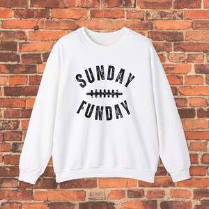 Op de afbeelding: Wit sweatshirt met een zwarte grafische afbeelding die "SUNDAY FUNDAY" zegt met een voetbalnaadontwerp in het midden.