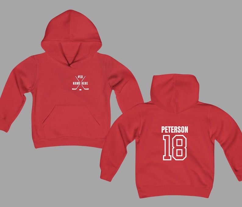 May include: Red hoodie with a front pocket and hood. The front features crossed hockey sticks and the text "#18 NAME HERE". The back displays "PETERSON" and the number "18" in white.