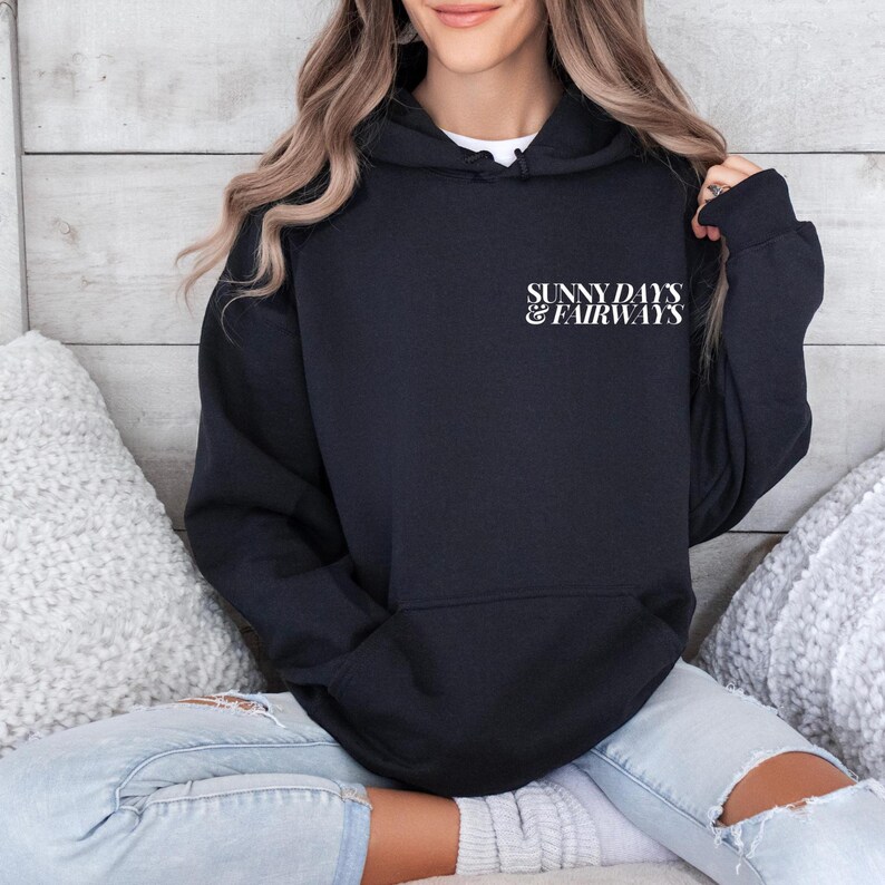 black golf themed hoodie with sunny days and fairways in a bold, trendy font on the back of the shirt. On the front, is a small sunny days and fairways graphic on the left chest