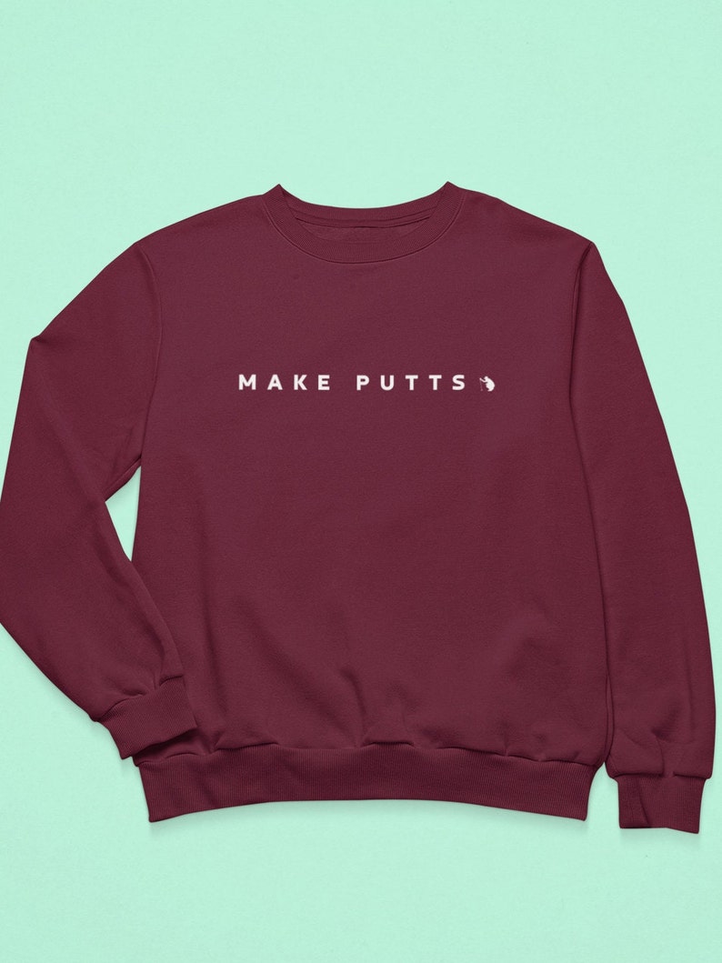 May include: Burgundy sweatshirt with the text "MAKE PUTTS" in white.