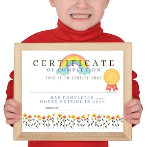 May include: A framed certificate with the text "CERTIFICATE OF COMPLETION" and "HAS COMPLETED HOURS OUTSIDE IN 2023!" A rainbow and gold medal graphic are at the top. The frame is light brown, and the certificate has a floral border.