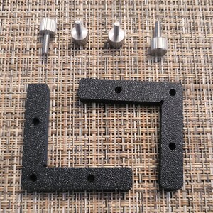 May include: Two black plastic corner brackets with four holes each and four silver metal screws.