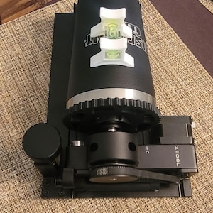 May include: A black and silver tool with a gear system and a level on top. The tool is labeled "XTOOL" and "C".