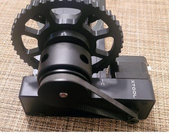May include: A black rotary tool with a belt drive system and a gear. The tool is labeled "XTOOL" and has a black plastic housing.