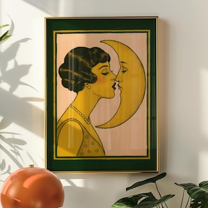 May include: Art Deco-style framed print featuring a woman kissing a crescent moon. The artwork has a gold frame with a green border. The woman is depicted in yellow with a pearl necklace, and the background is a soft pink.