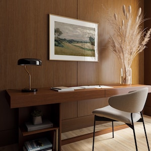 K&ouml;nnte beinhalten: Ein modernes Heimb&uuml;ro mit einem dunklen Holzschreibtisch, einer schwarzen und goldenen Schreibtischlampe und einem gerahmten Landschaftsbild. Ein grauer Stuhl, eine Vase mit getrockneten Pflanzen und B&uuml;cher sind ebenfalls zu sehen. Der Schreibtisch ist etwa 150 cm lang.