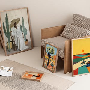 Op de afbeelding: Verschillende ingelijste kunstdrukken, waaronder woestijnlandschappen en een portret, worden gepresenteerd in de buurt van een stoel. Een print toont een persoon in een witte jurk en hoed met cactussen. Andere prints tonen woestijnsc&egrave;nes met ruiters.