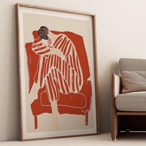 Puede incluir: Una ilustración enmarcada de una persona sentada en una silla roja. La persona lleva un atuendo a rayas y tiene la cabeza gacha.