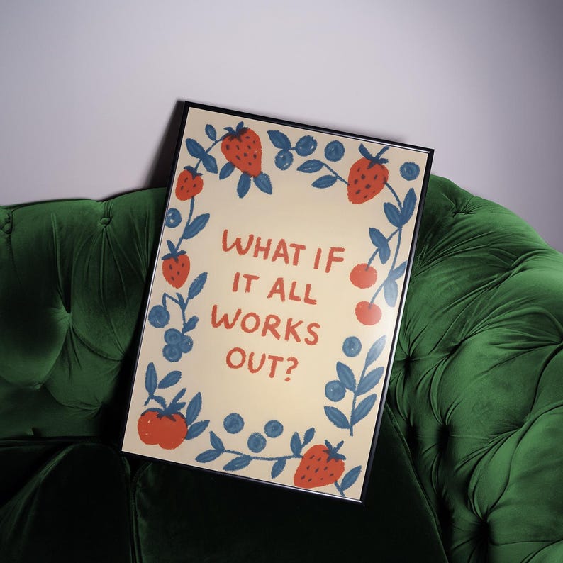 K&ouml;nnte beinhalten: Ein gerahmter Kunstdruck mit dem Text "WHAT IF IT ALL WORKS OUT?" umgeben von einem Rand aus illustrierten Erdbeeren, Blaubeeren und Kirschen. Der Druck hat einen cremefarbenen Hintergrund und liegt auf einem gr&uuml;nen Samtsofa.