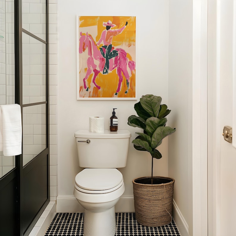 Pu&ograve; includere: Un water bianco con il coperchio chiuso in un bagno con pareti in piastrelle bianche a metro. Un dipinto incorniciato di una persona che cavalca un cavallo rosa &egrave; appeso sopra il water. Una pianta in vaso con foglie verdi si trova sul pavimento accanto al water.