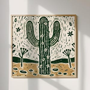 以下が含まれることがあります： 白い花が咲いた緑色のサボテンが描かれたリノカット版画。サボテンは、小さな植物と薄い茶色の背景を持つ砂漠の風景に囲まれています。