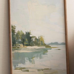 Può includere: Un dipinto astratto incorniciato di un paesaggio con un lago e alberi. Il dipinto è realizzato in tonalità di blu, verde e bianco.