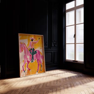 Pu&ograve; includere: Un dipinto incorniciato di una persona a cavallo di un cavallo rosa. La persona indossa un cappello da cowboy e una camicia rosa. Lo sfondo &egrave; giallo.