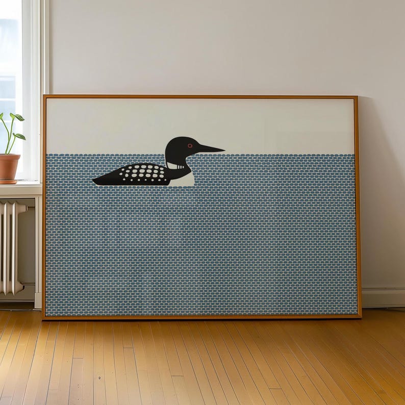 May include: A framed art print featuring a stylized illustration of a loon swimming in water. The loon is black and white with a red eye, set against a blue patterned background. The artwork is encased in a wooden frame, suitable for wall decor.