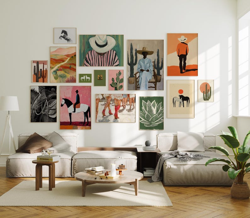 Op de afbeelding: Een galerijmuur met diverse ingelijste kunstwerken met een zuidwestelijk thema. De kunstwerken omvatten schilderijen van cactussen, paarden en figuren met hoeden, in een mix van kleuren als oranje, roze en groen. De opstelling bevindt zich boven een moderne woonkamer.