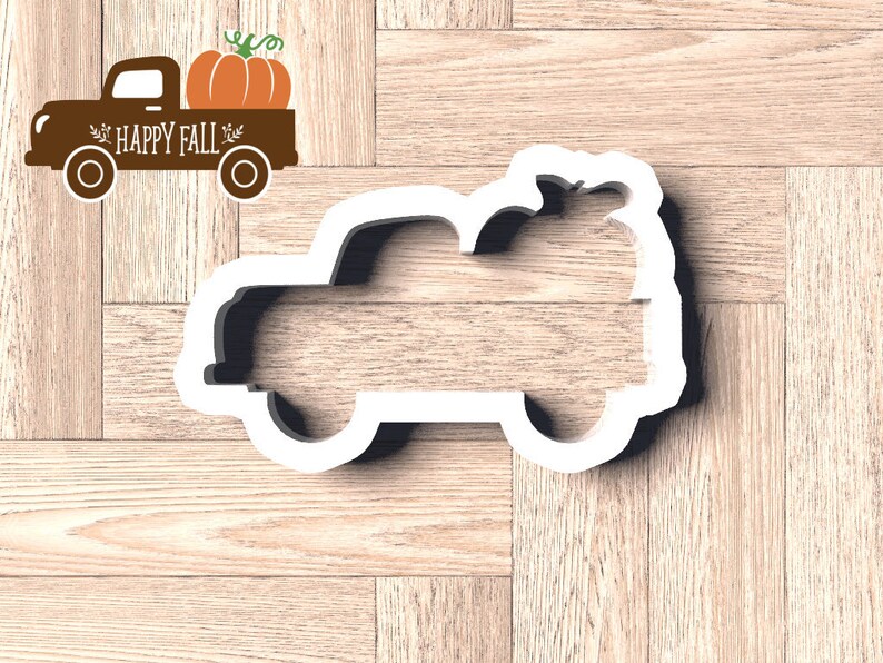 Pu&ograve; includere: Un tagliabiscotti bianco a forma di camion con una zucca nel cassone. Accanto, una grafica di camion marrone con una zucca, le parole "HAPPY FALL" e foglie decorative.